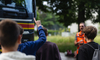 Jugendlicher stellt Frage während Verkehrssicherheitslektion vor Lastwagen.