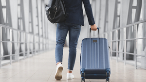 Mann zieht Koffer hinter sich her im Flughafen