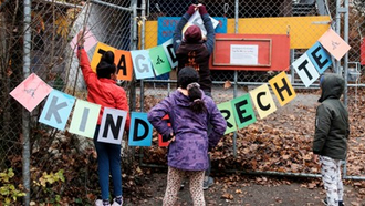 vier Kinder, die eine Schriftgirlande "Tag der Kinderrechte" aufhängen.