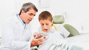 Zahnarzt erklärt einem Kind etwas an einem Gebissmodell