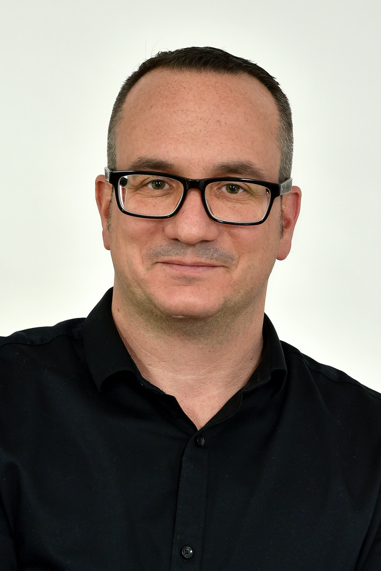 Stefan Frech Portärt eines Mannes mit Brille und schwarzem Hemd. Er hat kurze Haare und blickt in die Kamera.