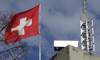 Mehrere Sirenen auf einem Dach. Gross im Bild ist eine Schwizer Flagge.