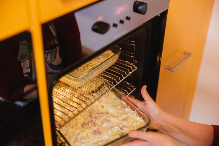 Die Köchin schiebt den Nudel-Sauerkraut-Auflauf in den Ofen