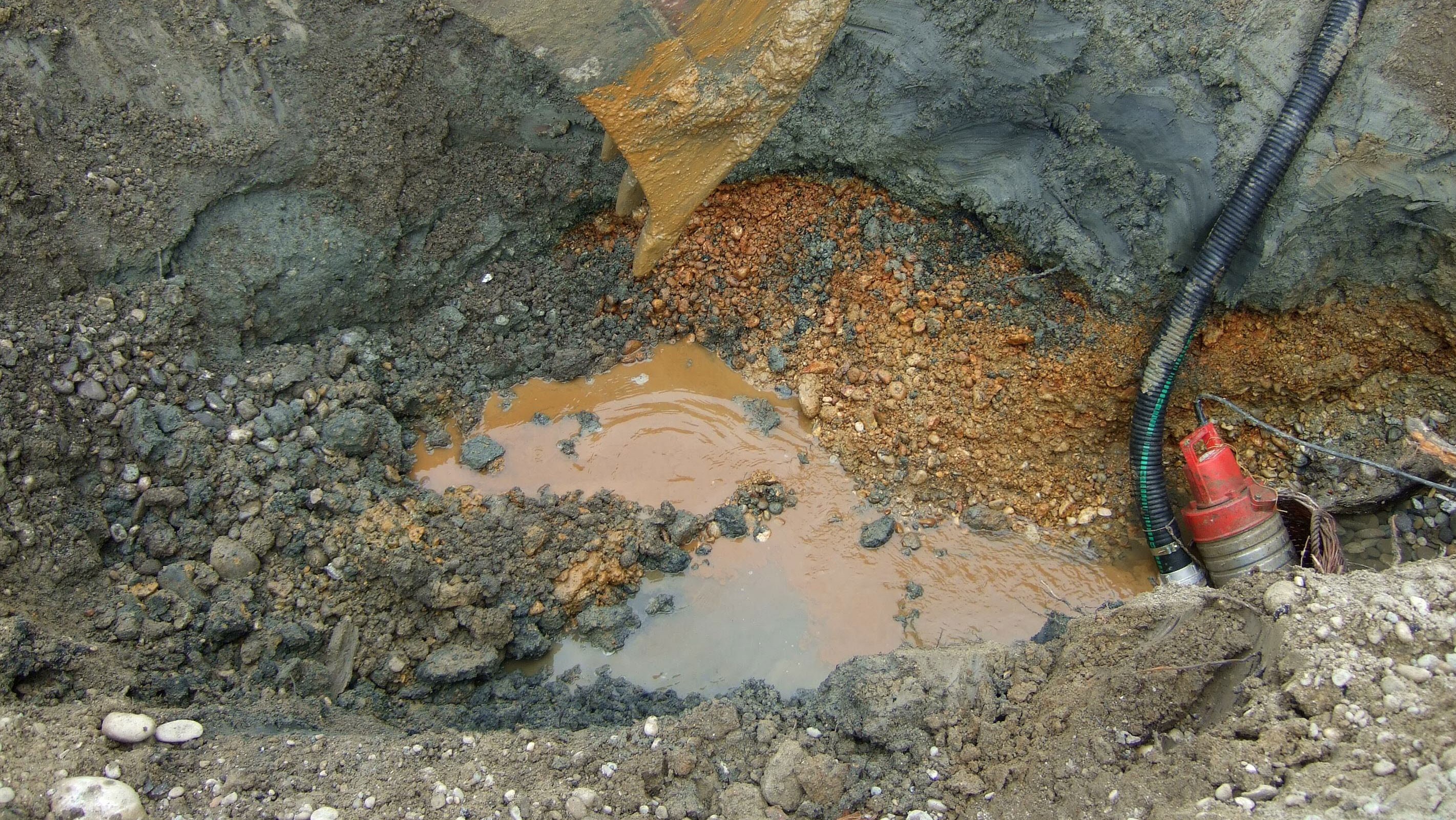 Baggerschaufel mit Aushub im Grundwasser