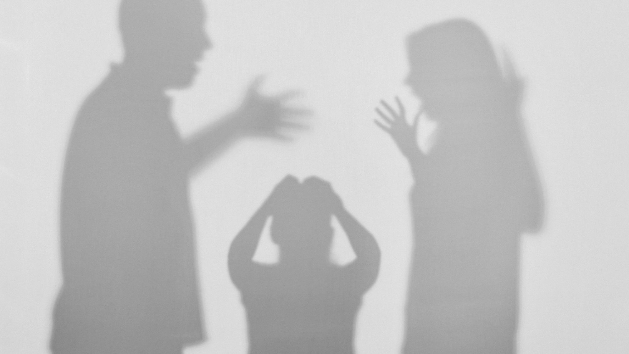 Schatten eines sich streitenden Paars und einem sich duckenden Kind in der Mitte.
