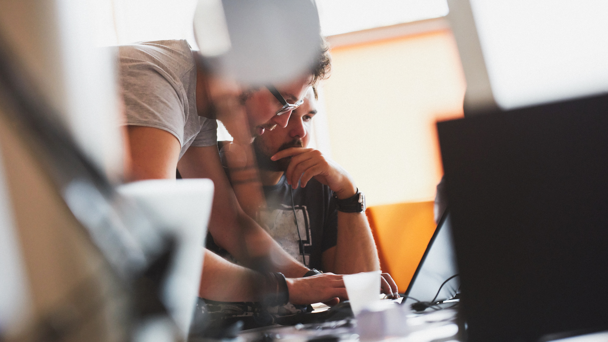 Mann erklärt einem anderen Mann etwas am Computer