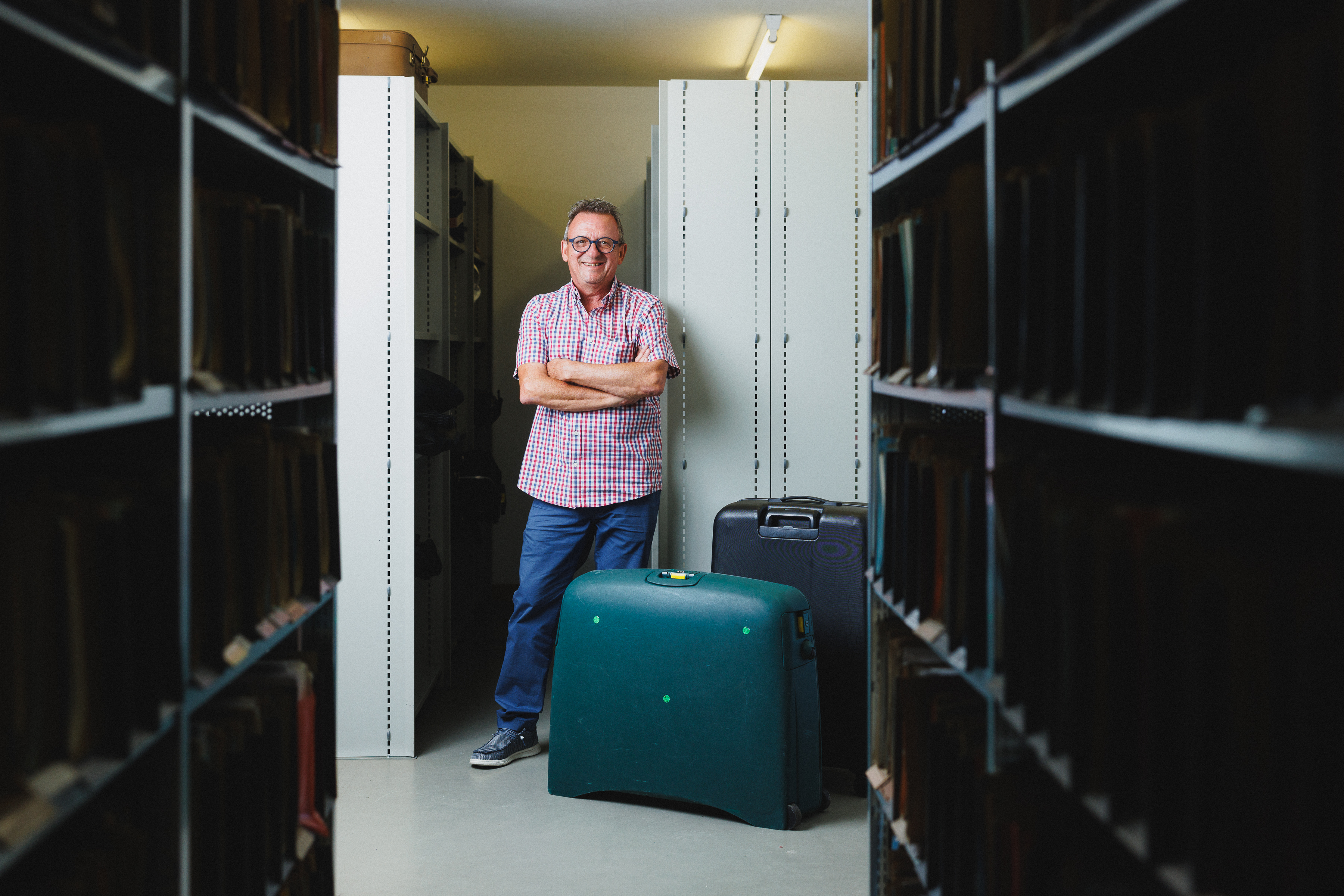 Alain Siegenthaler steht vor Koffern im Archiv des Migrationsamts