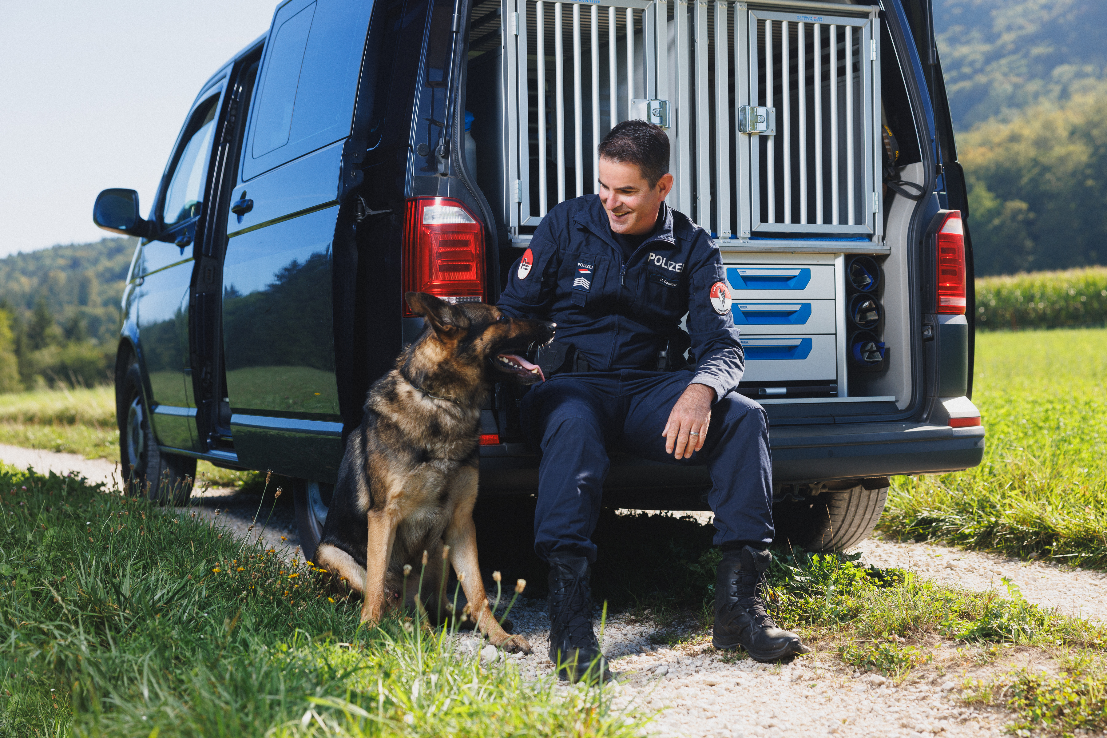 Ulrich Oppliger mit seinem Hund Jedi sitzend vor einem Dienstwagen