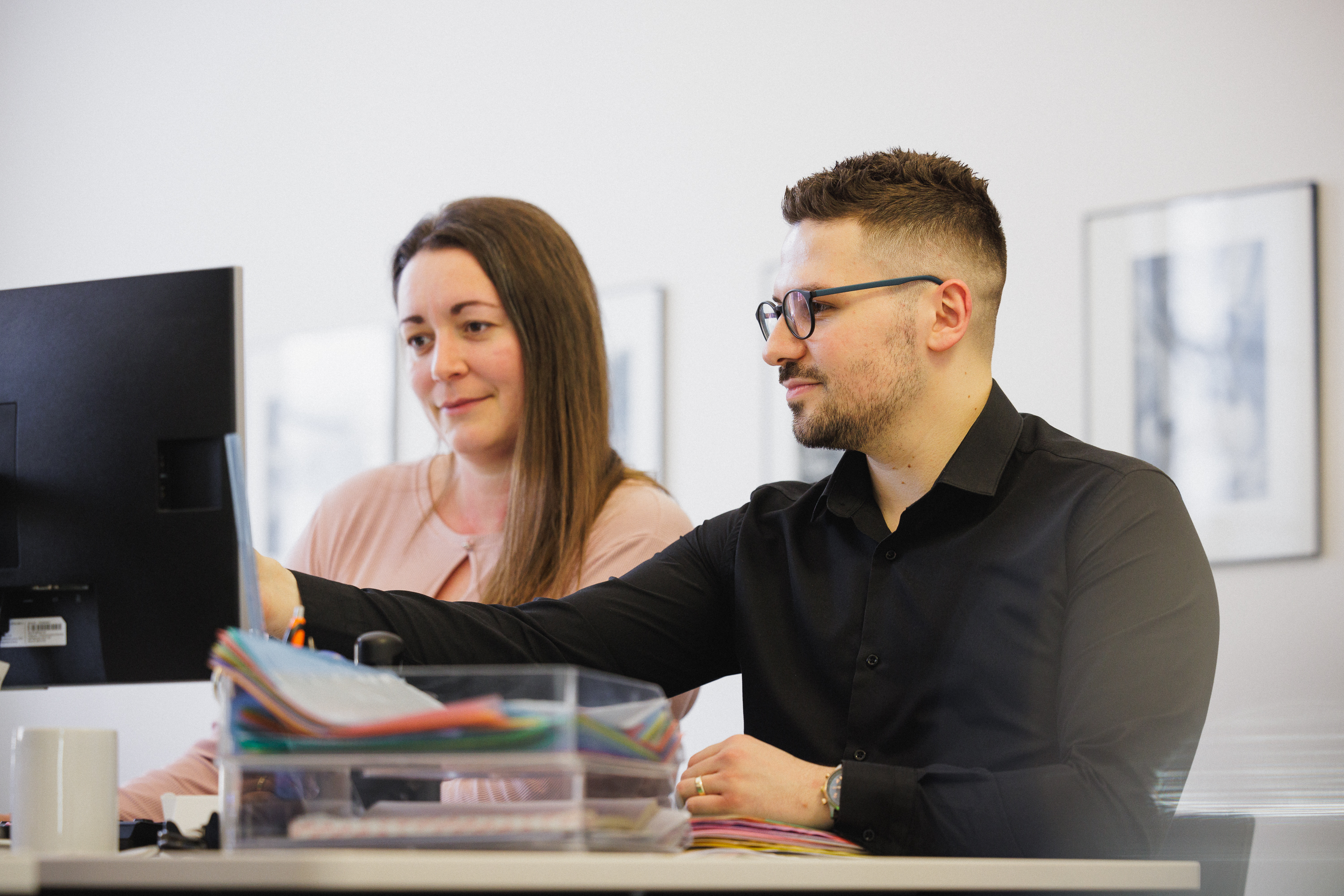 Xhevat Vasija und Sandra Salini vom Kanzlei-Team vor dem Computer