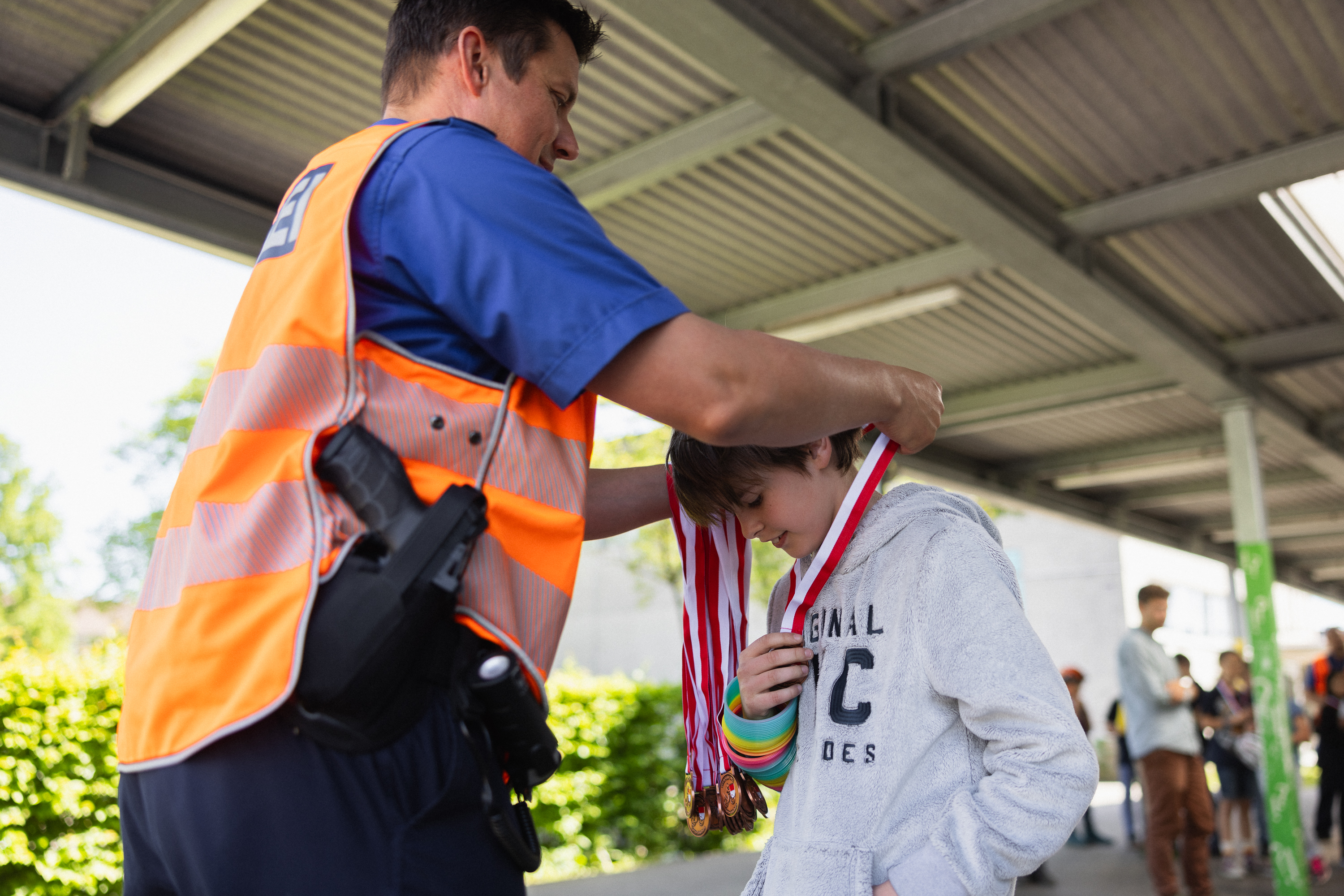 Ein Kind erhält nach bestandener Veloprüfung eine Medaille von der Polizei