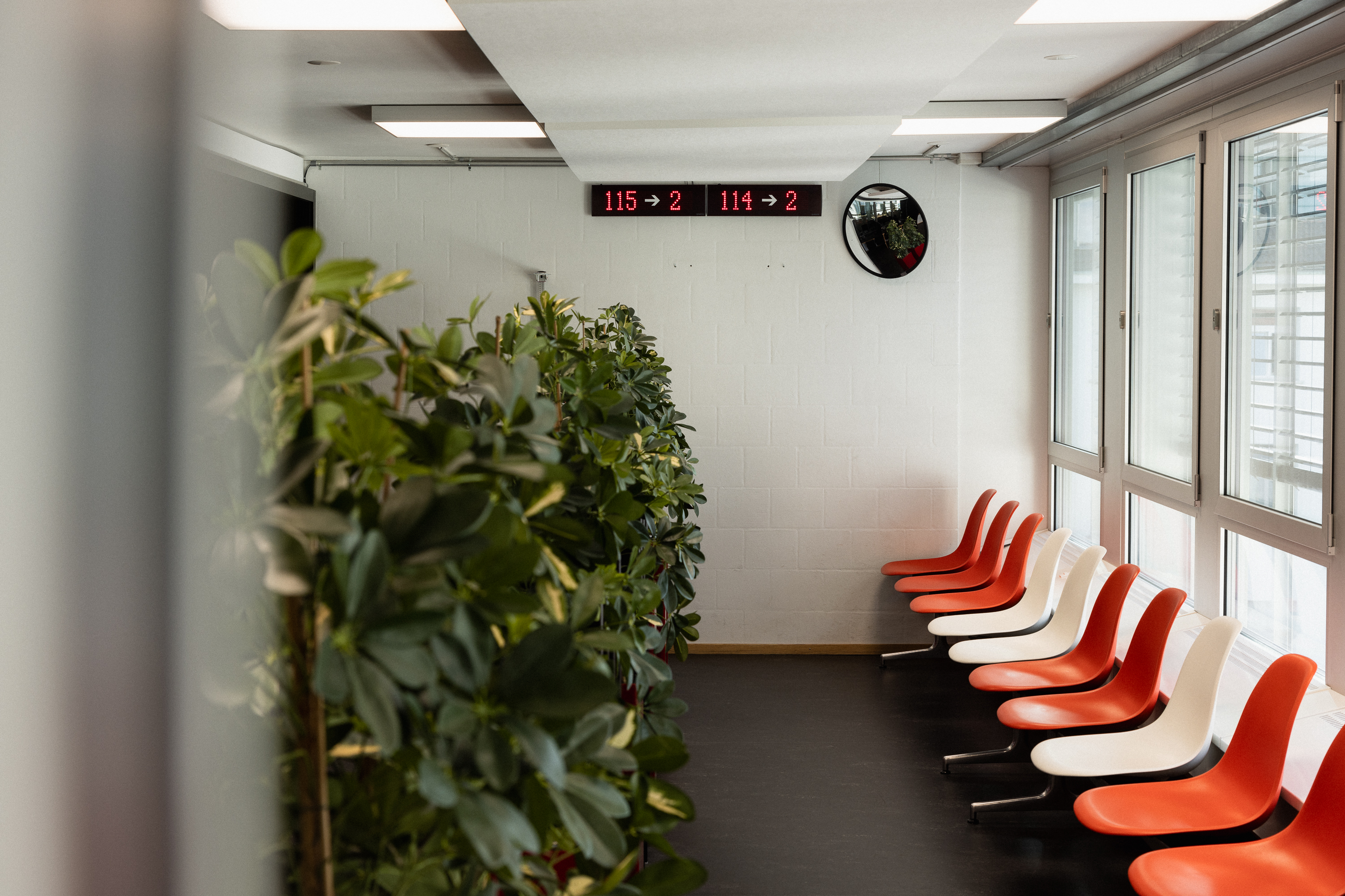 Wartebereich beim Schalter mit orangen und weissen Sitzen