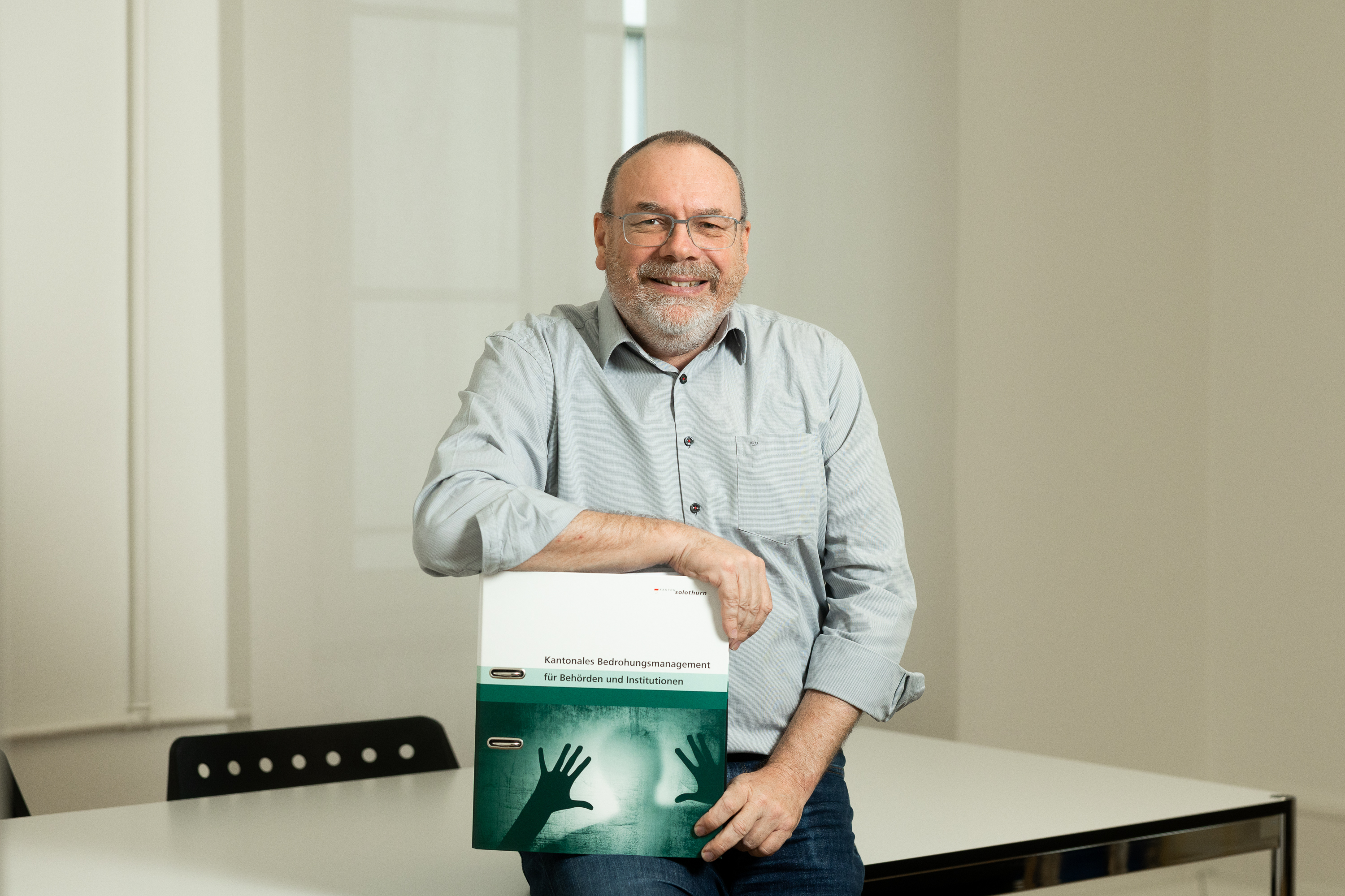 Rolf Flückiger zeigt das Handbuch des Bedrohungsmanagements