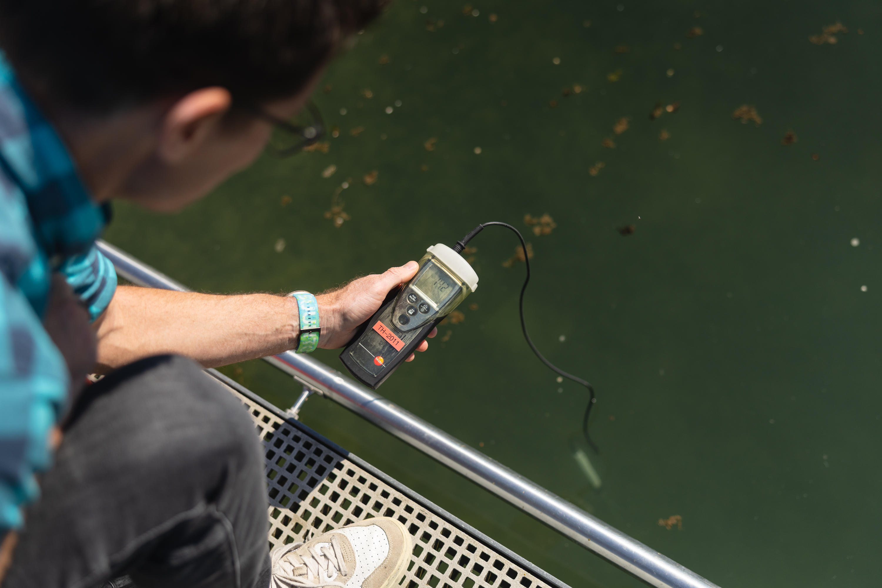 Simon Stüdeli misst Wasserqualität mit digitalem Gerät am Steg.