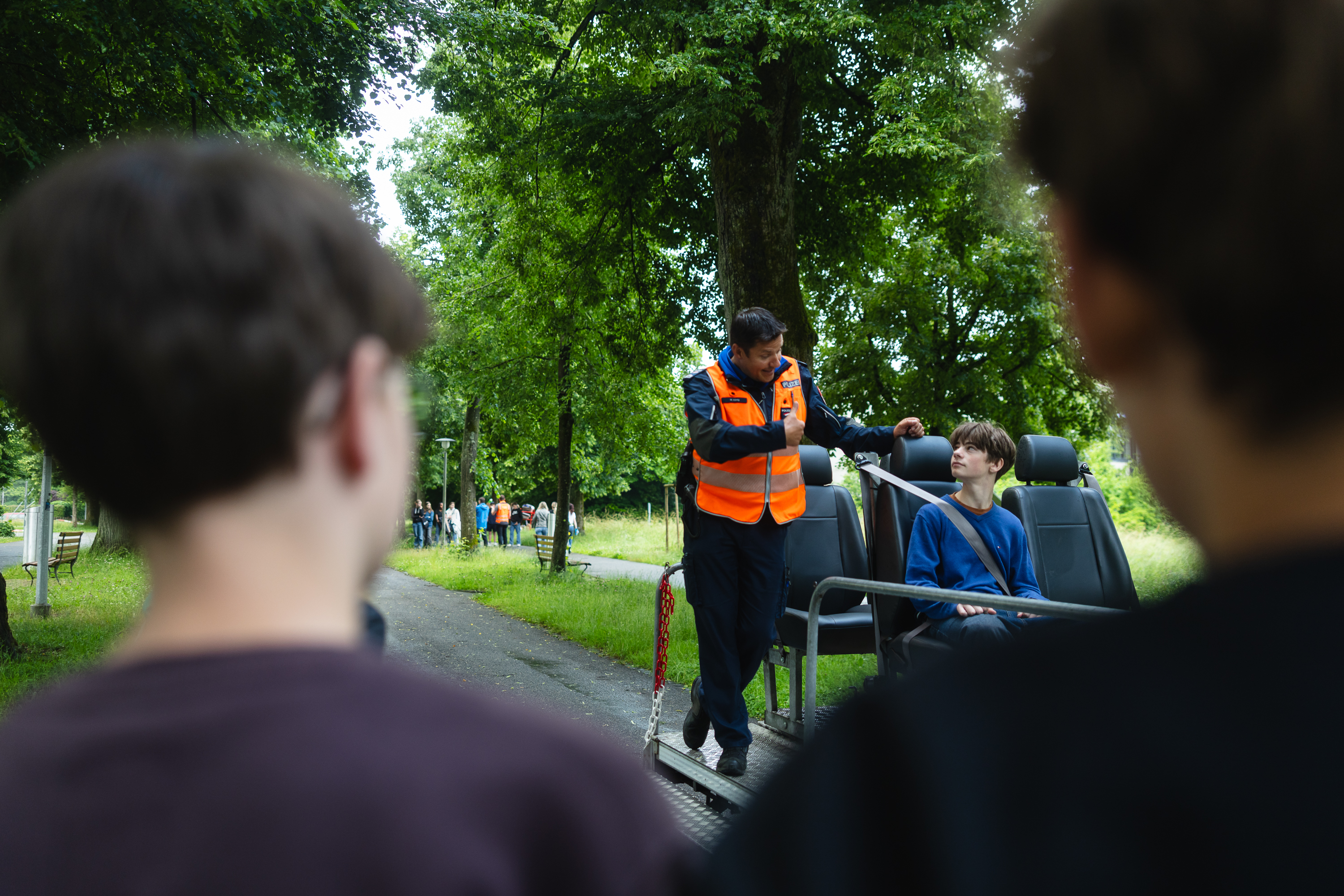 Polizist zeigt Jugendlichen im Aufprallsimulator die Bedeutung des Anschnallens.