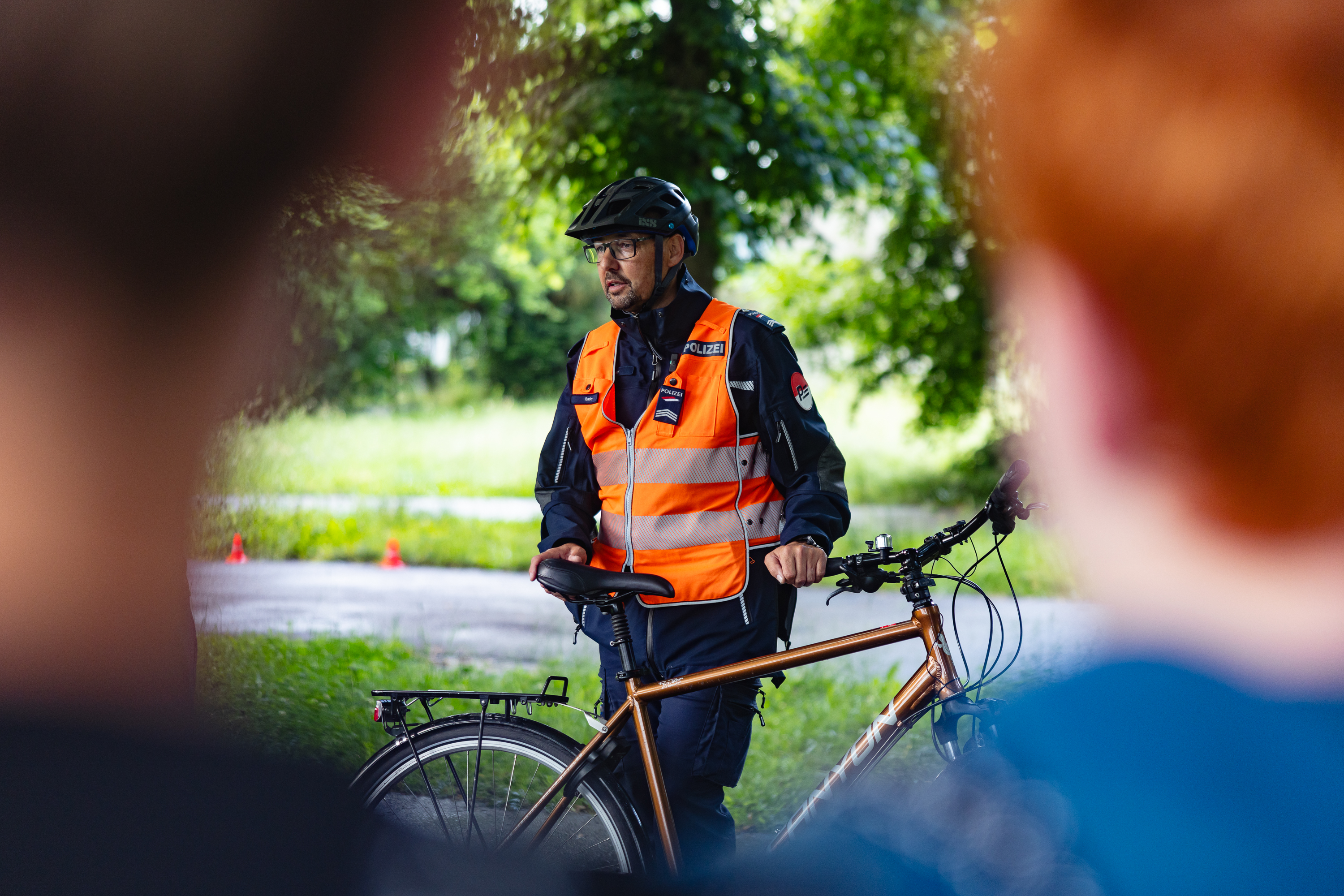 Polizist mit Velohelm erklärt Jugendlichen die Regeln im Strassenverkehr.