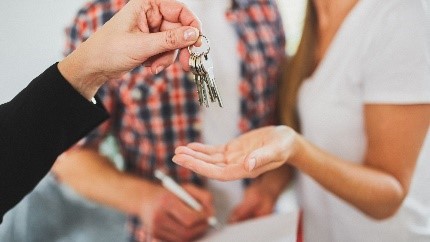 Die Vermieterin legt den Hausschlüssel in die Hand der Mieterin.