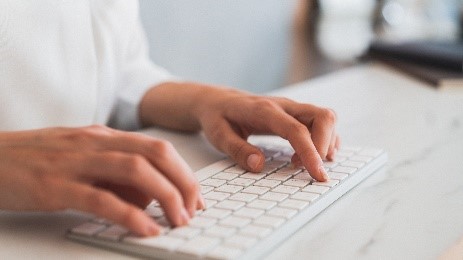 Eine Frau schreibt auf einer Computer Tastatur.