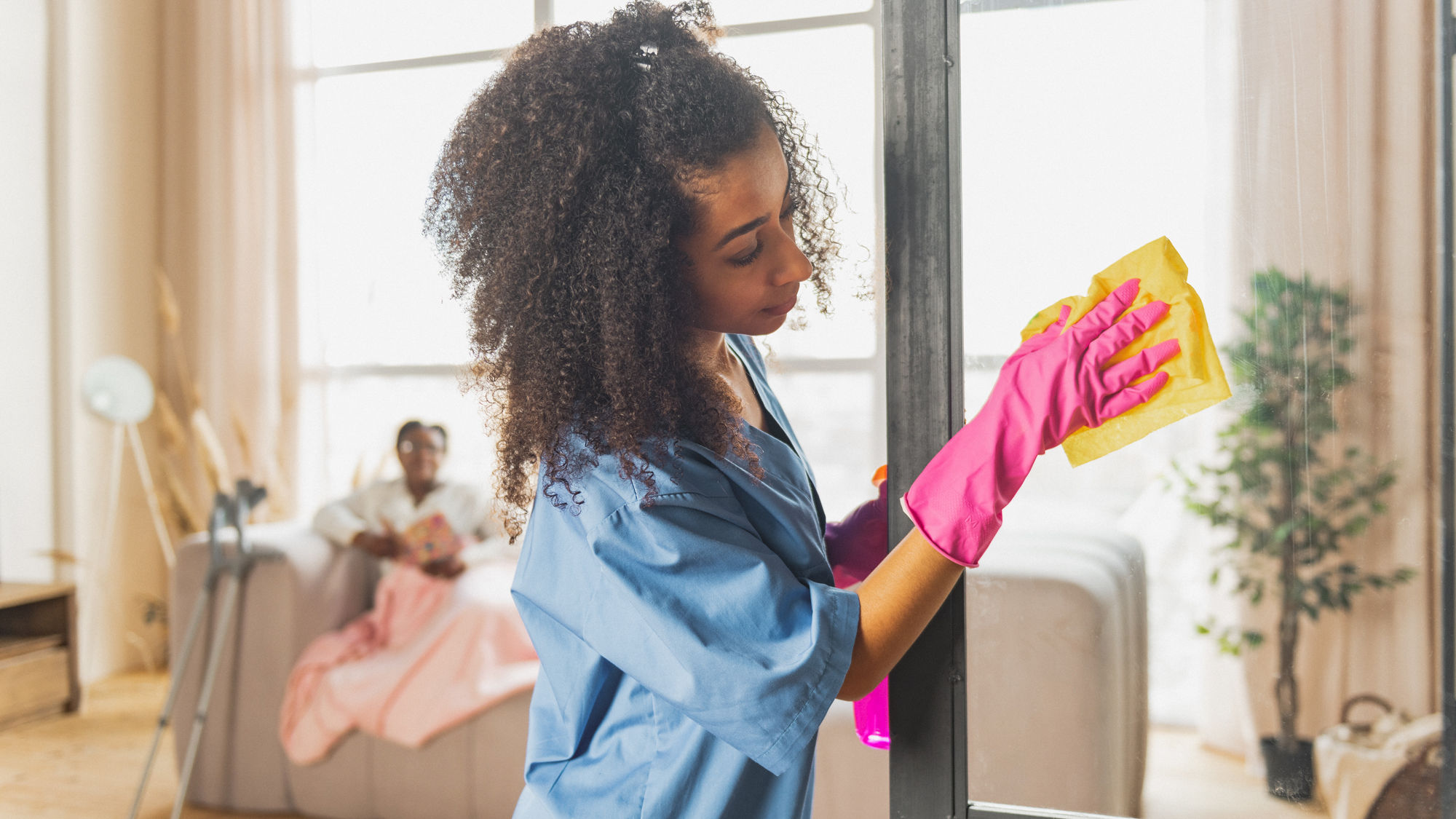 Eine Frau putzt in einer Wohnung eine Glasscheibe