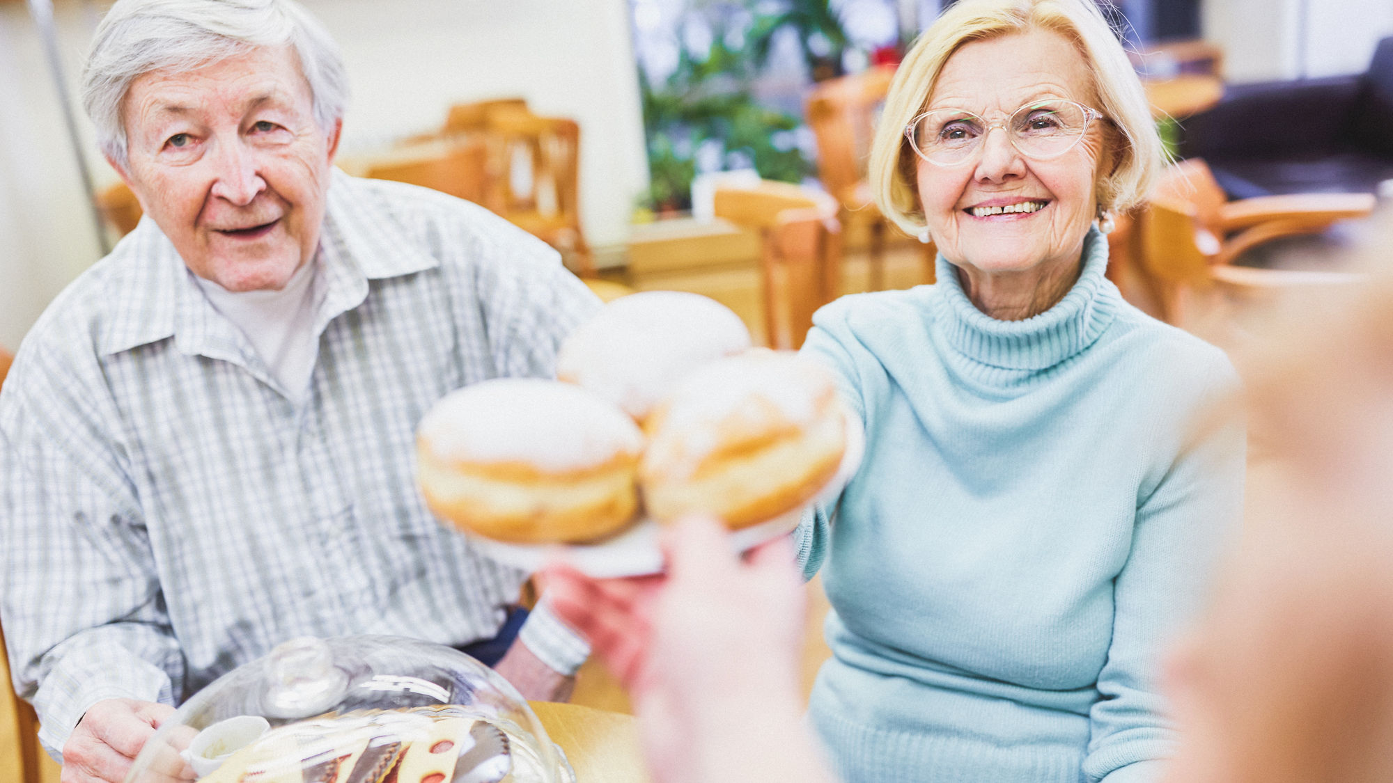 Eine Seniorin und ein Senior werden mit einem Dessert bedient