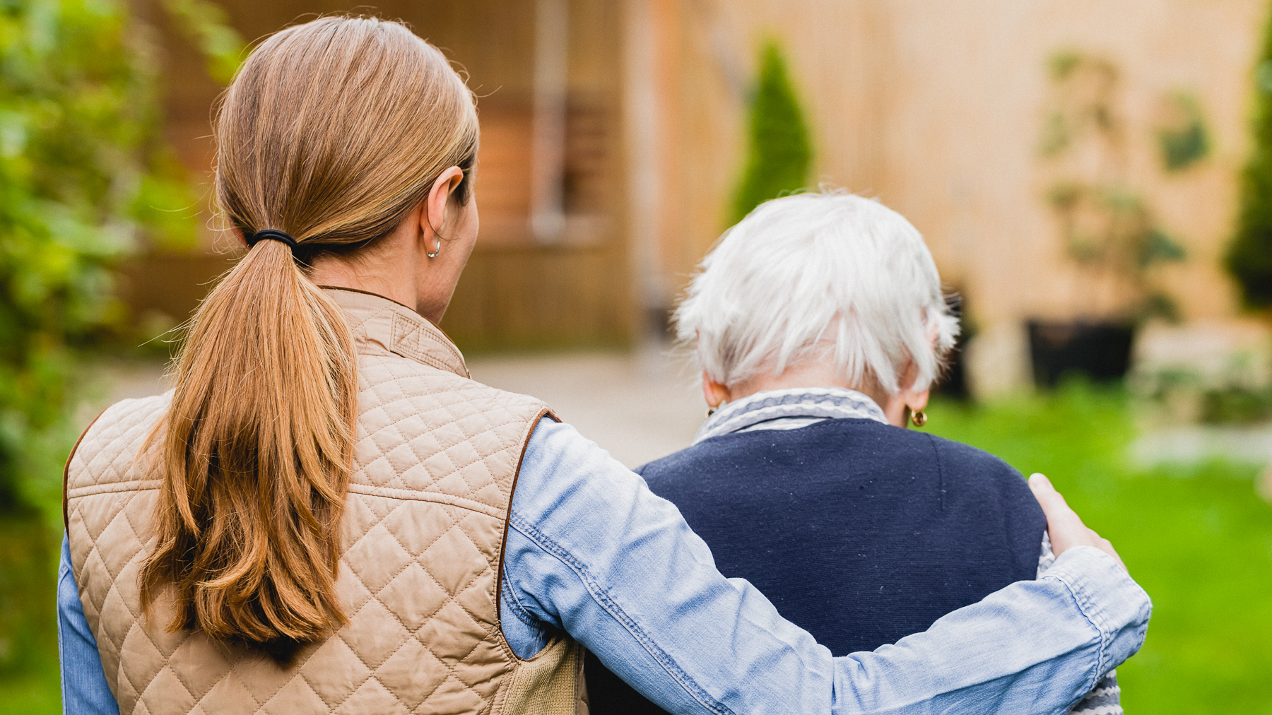 Eine Frau hilft einer älteren Person beim Gehen.