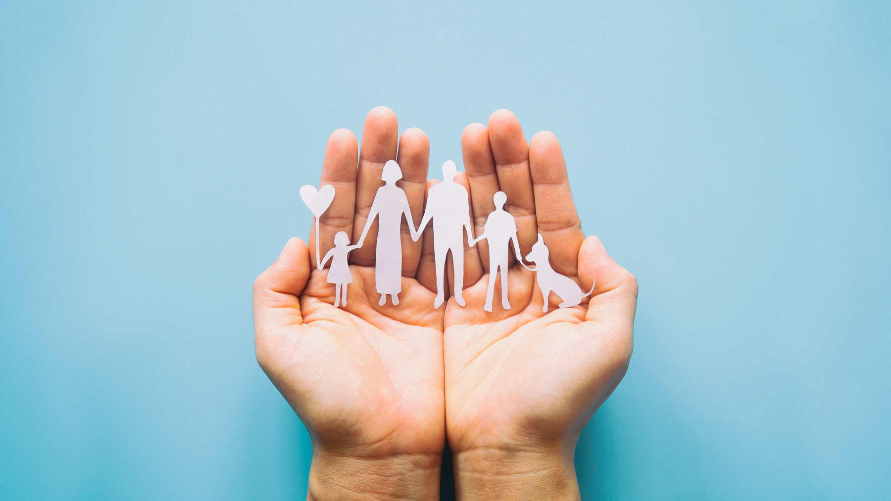 Hände halten einen Scherenschnitt, der eine Familie darstellt.
