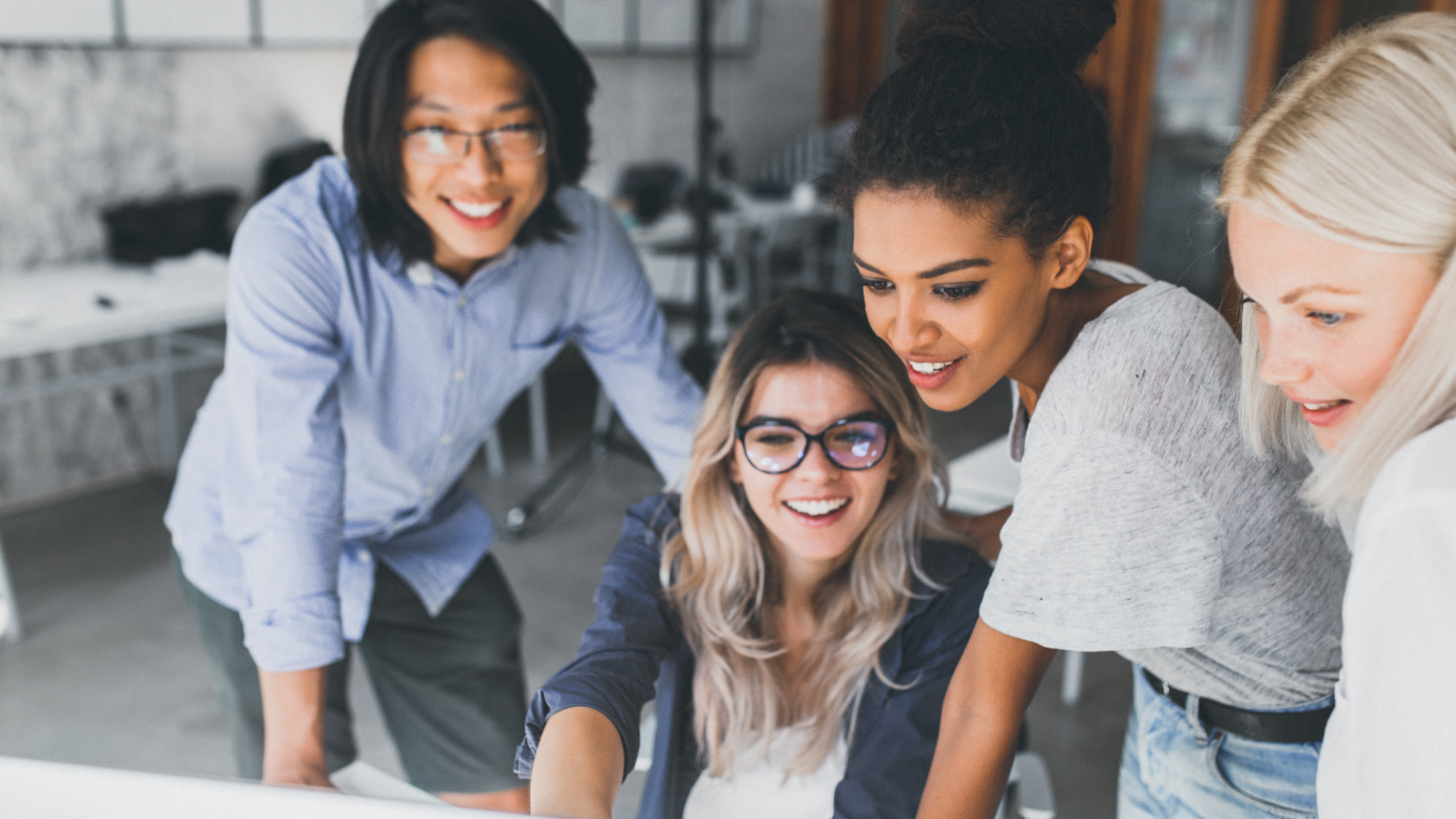 Gruppe von jungen Leuten lachen zusammen uns schauen in den Computer
