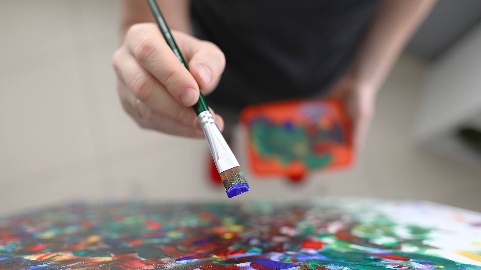 Kunstschaffende Person mit Staffelei, Farbpalette und Pinsel