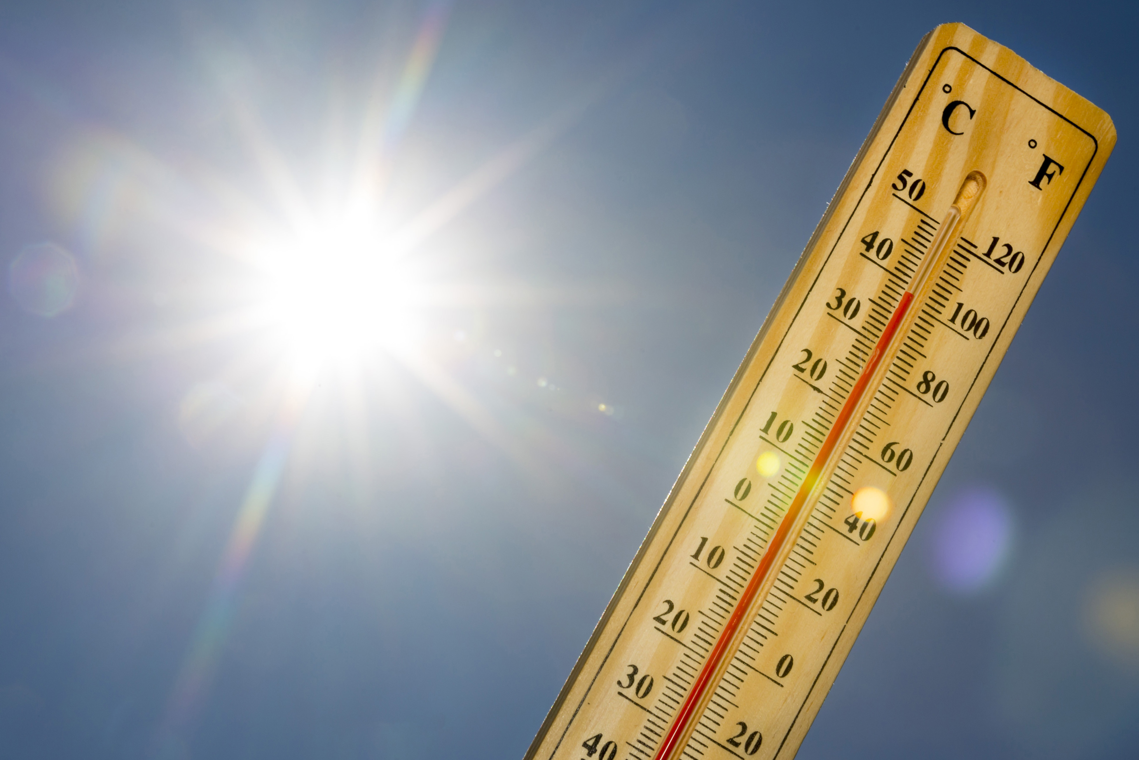 Bild von der strahlenden Sonne am blauen Himmel, daneben ein Thermometer