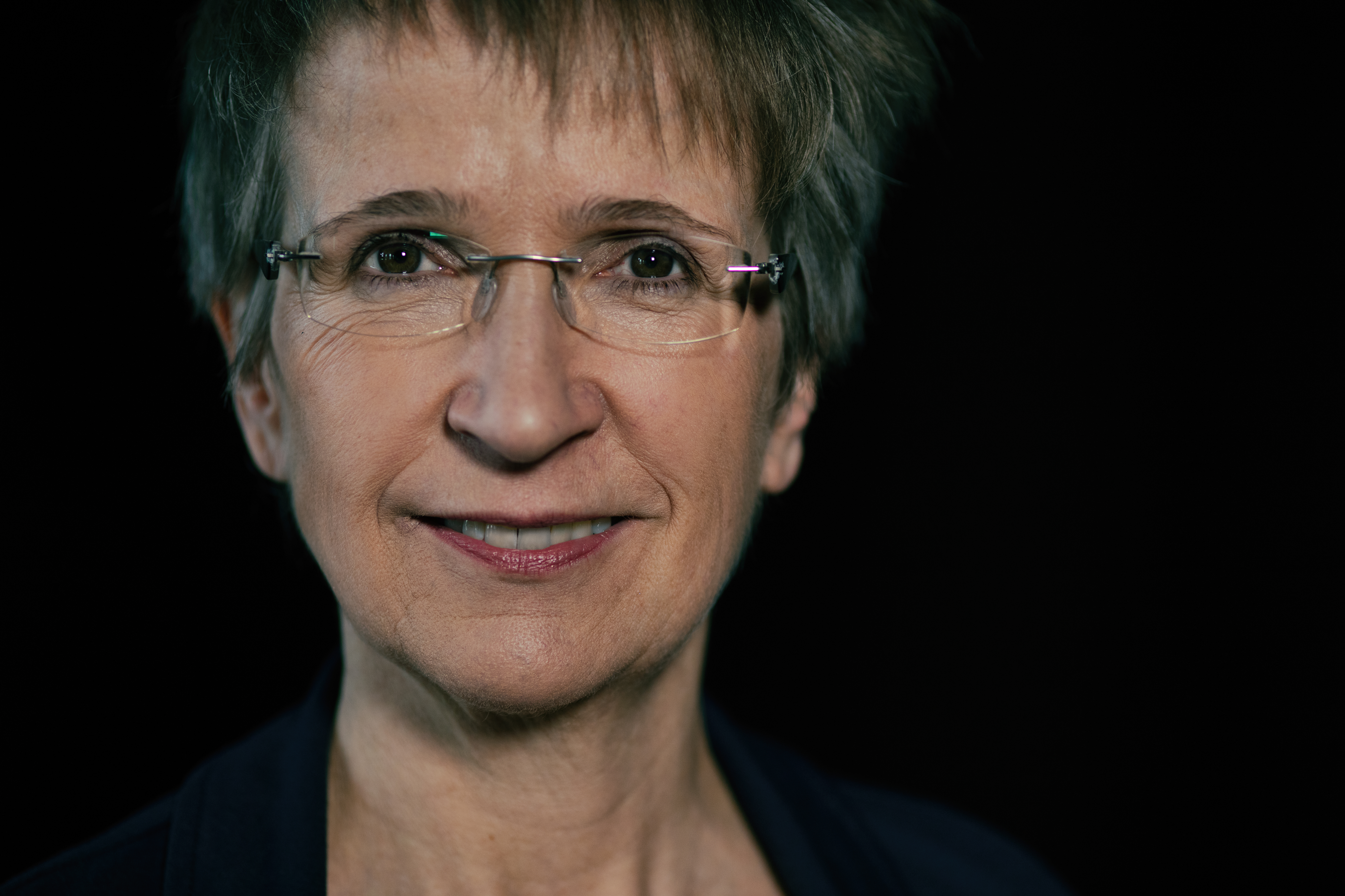 Käthi Vögeli blickt in die Kamera vor schwarzem Hintergrund.